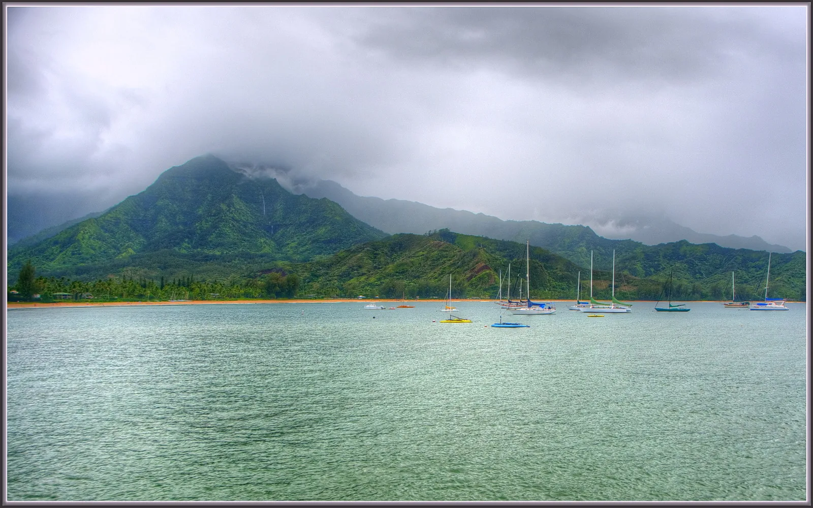 Low clouds over the green mountains and moored sailboats of Hanalei Bay on Kauai