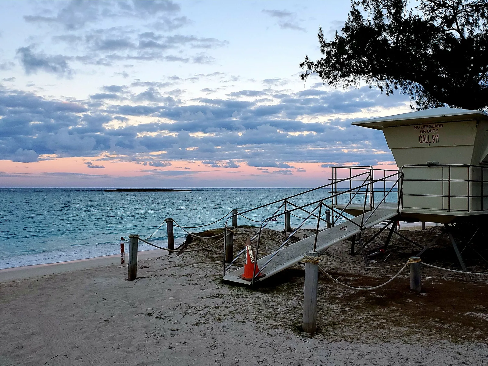 A lifeguard tower on the sand at Kailua Beach at dusk, with islands offshore