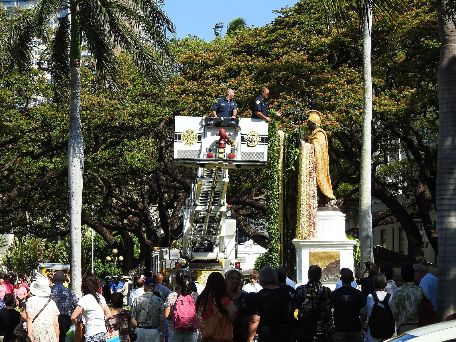 Firefighters draping long lei on the gilded King Kamehameha statue in downtown Honolulu