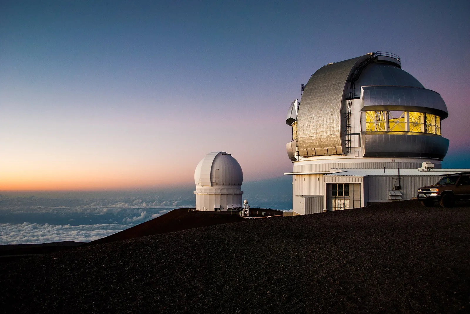 Telescope domes on the summit of Mauna Kea at sunset above the clouds