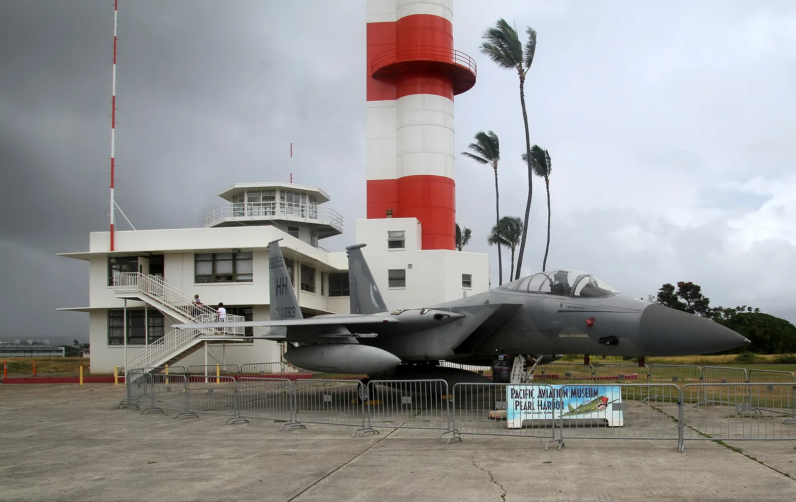 The red and white Ford Island control tower with a fighter jet on display at the Pearl Harbor Aviation Museum