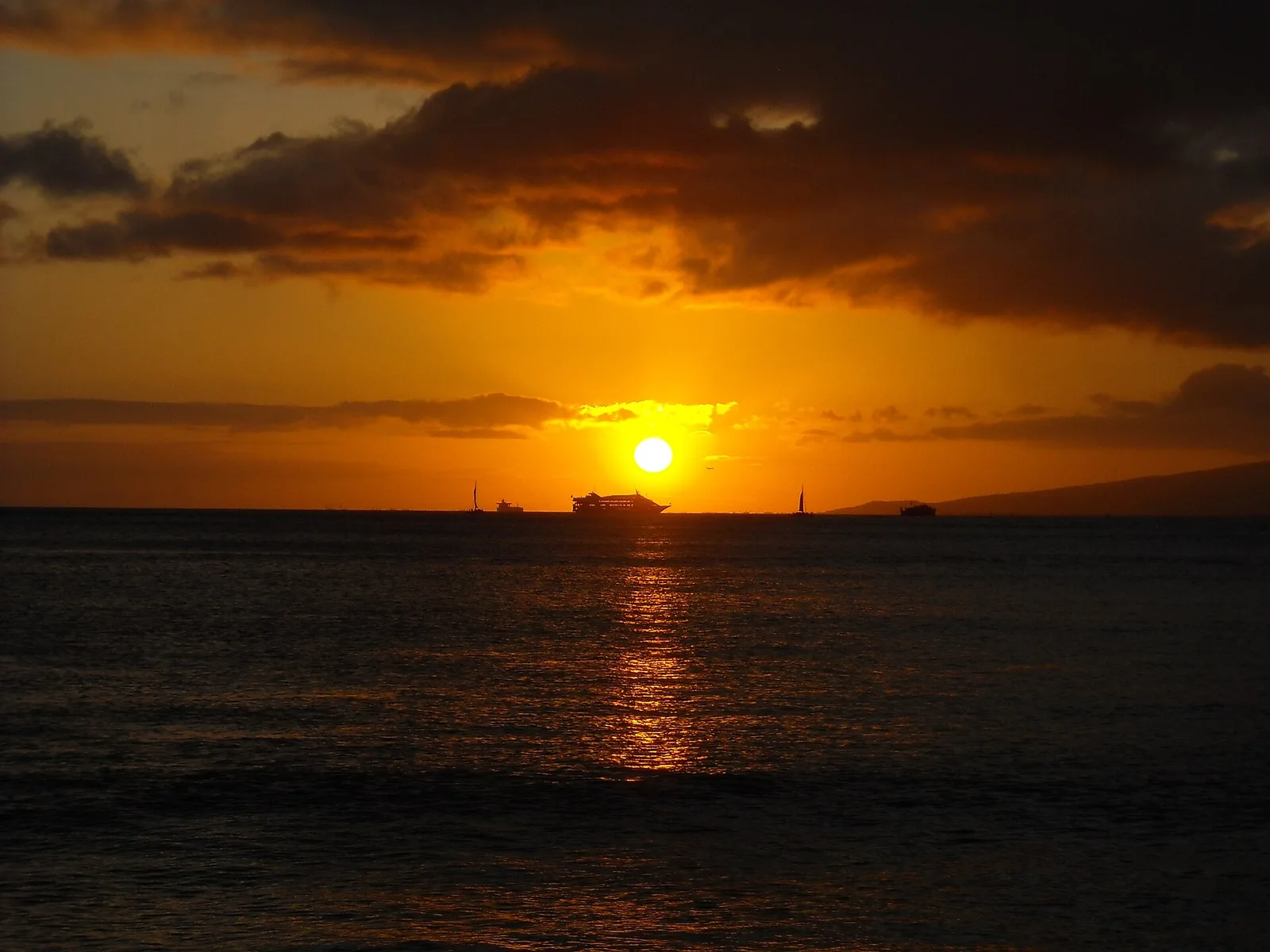 The sun setting over the ocean from Queen's Surf Beach, with ships on the horizon