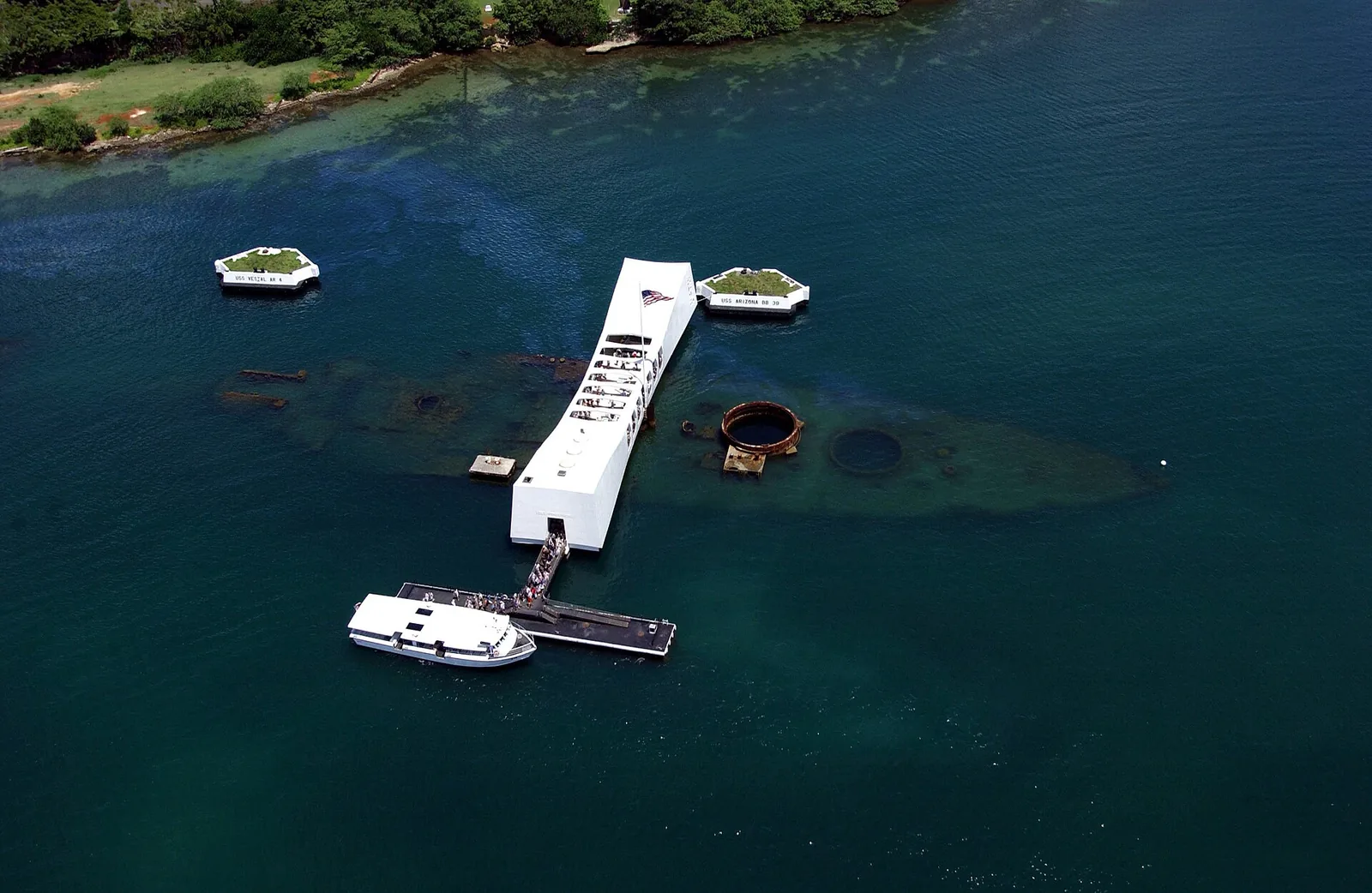 Aerial view of the white USS Arizona Memorial spanning the sunken battleship in Pearl Harbor