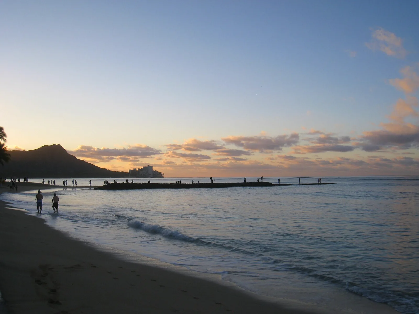 Waikiki Beach at dusk with the dark outline of Diamond Head and a groin running out to sea
