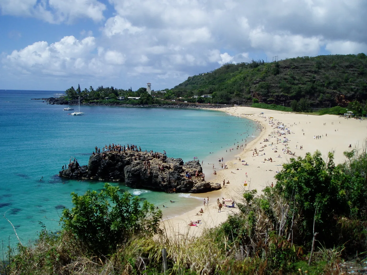 Waimea Bay on Oahu's North Shore in calm summer conditions with swimmers near the jump rock