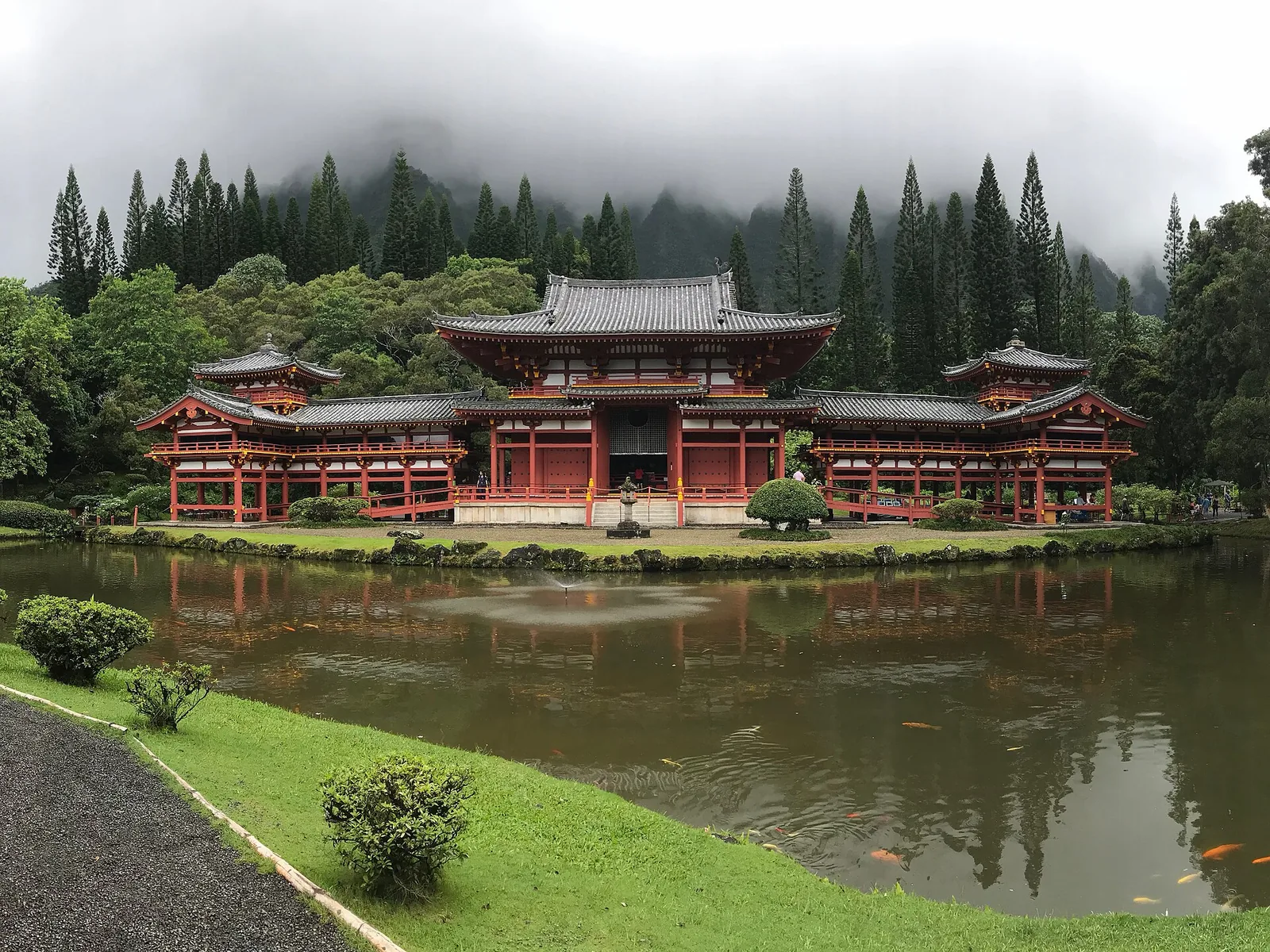 The red Byodo-In Temple in the Valley of the Temples, seen across its pond beneath forested hills