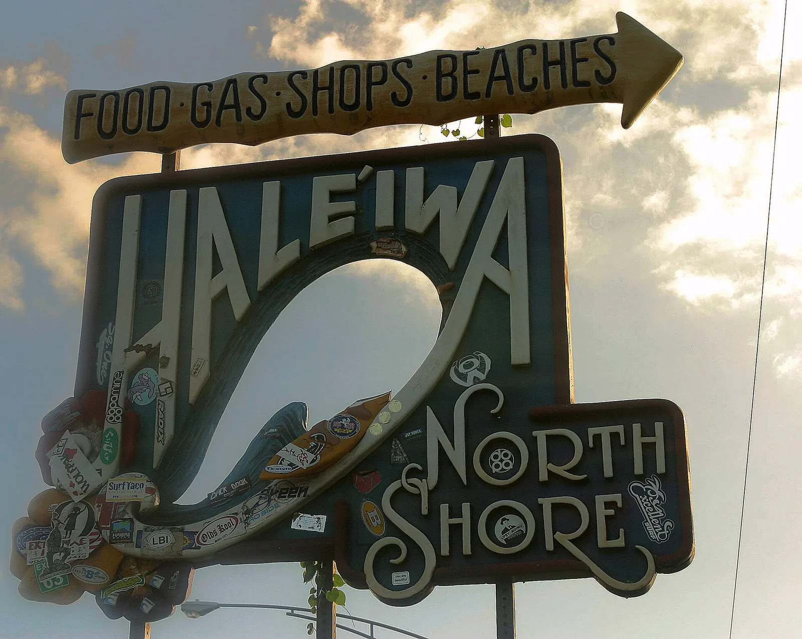 The carved wooden Haleiwa sign with a surfer design and an arrow pointing to food, gas, shops and beaches