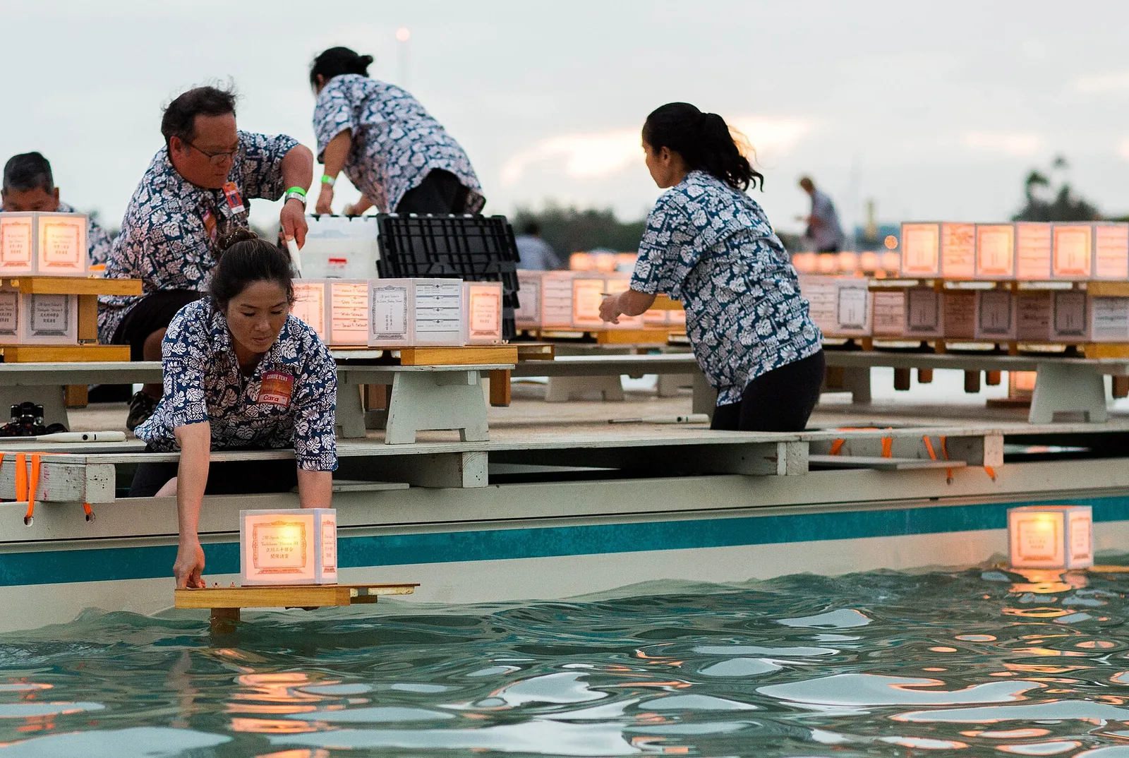 People setting glowing paper lanterns afloat at the Lantern Floating Hawaii ceremony at Ala Moana Beach Park, one of the most moving Hawaii events