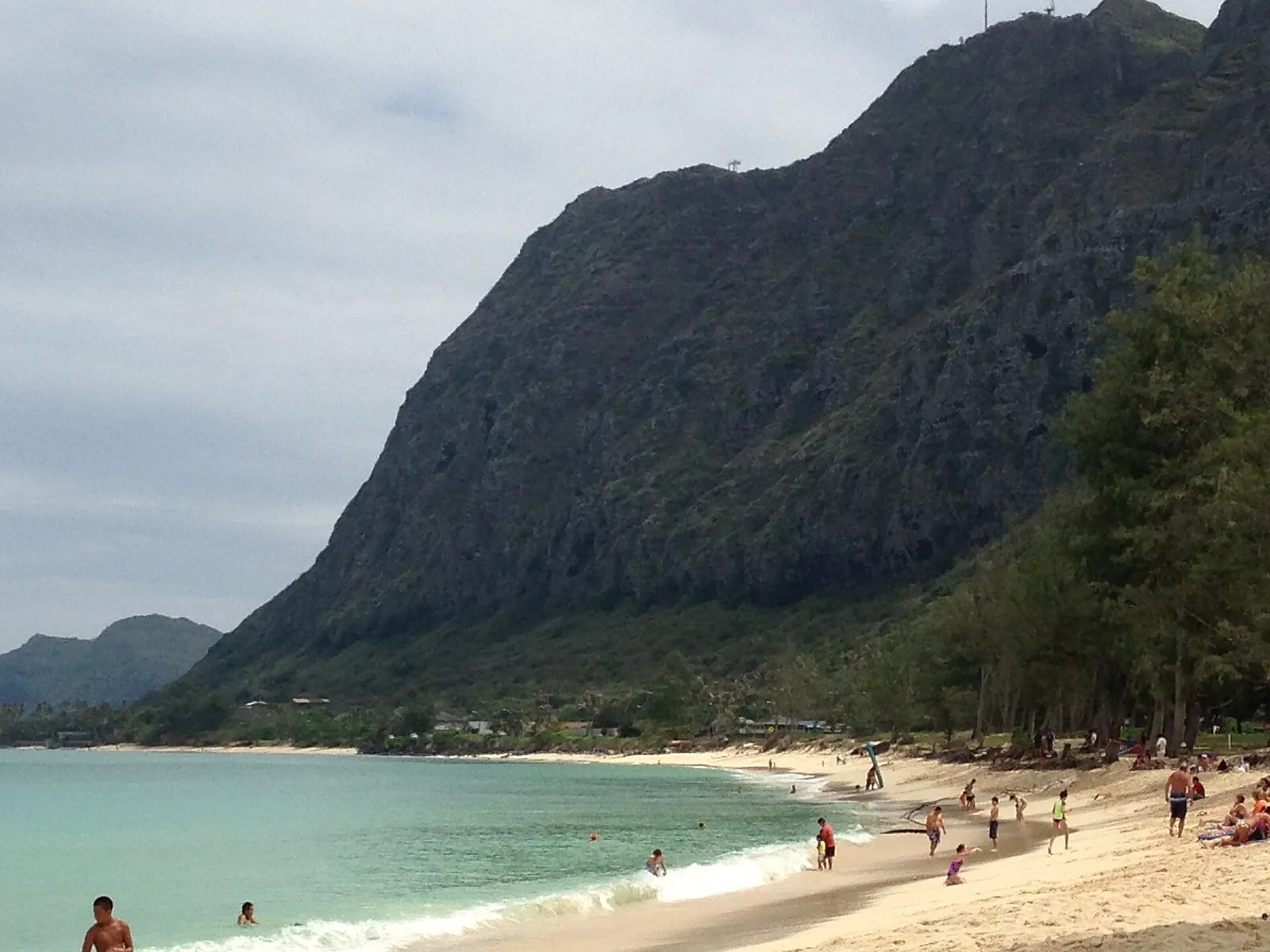 Families wading in the shallows at Waimanalo Beach Park below the Koolau cliffs, a classic beach day for Hawaii with kids