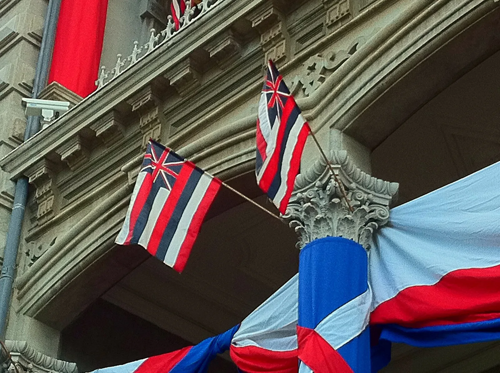 Hawaiian flags and red, white and blue bunting on the ornate facade of Iolani Palace