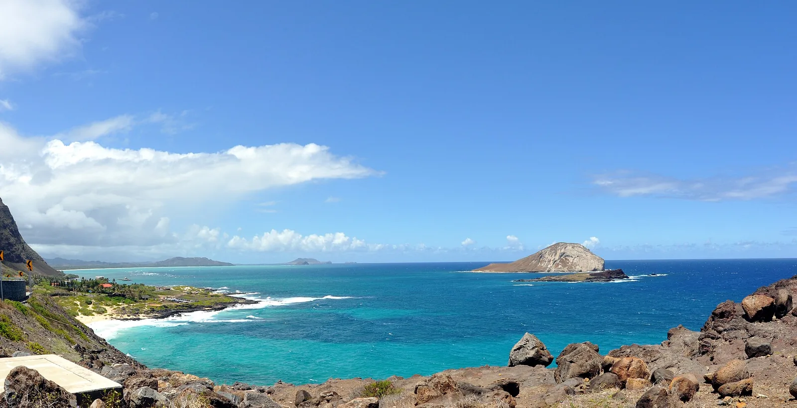 Turquoise sea and a rocky islet off the Makapuu coastline under a bright blue sky