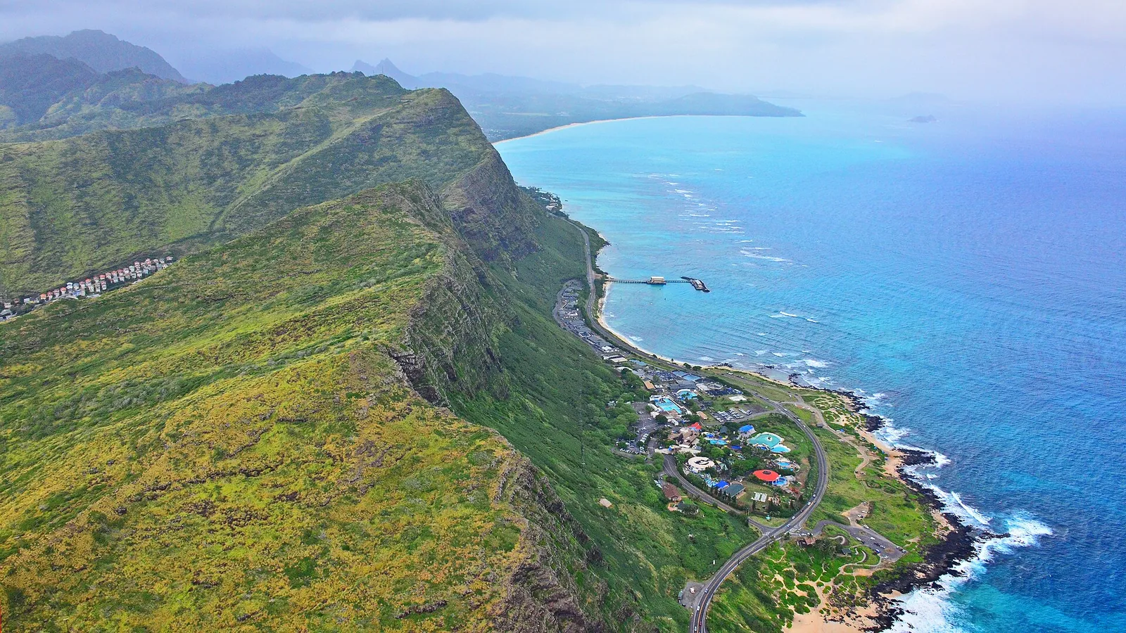 Aerial view of the Makapuu coast with Sea Life Park and the road below steep green cliffs and turquoise sea
