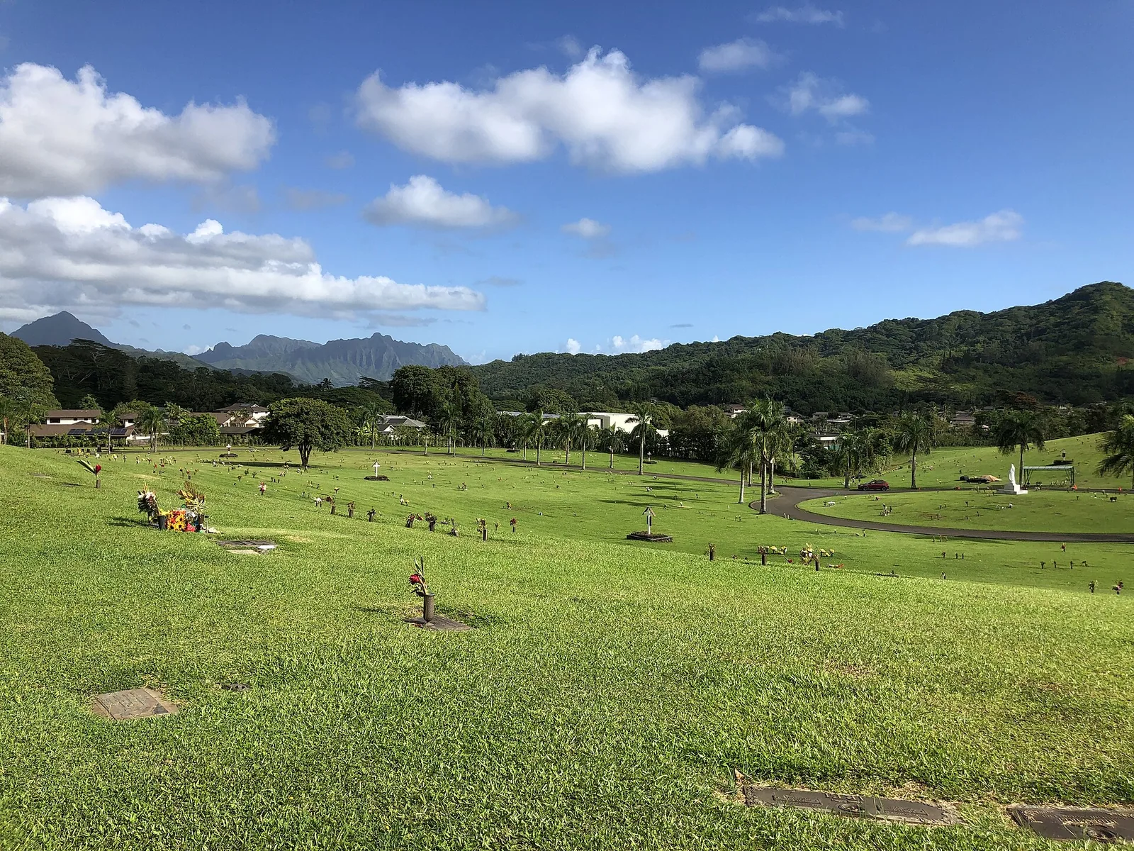 Wide green lawns of the Valley of the Temples Memorial Park under a blue sky with mountains in the distance