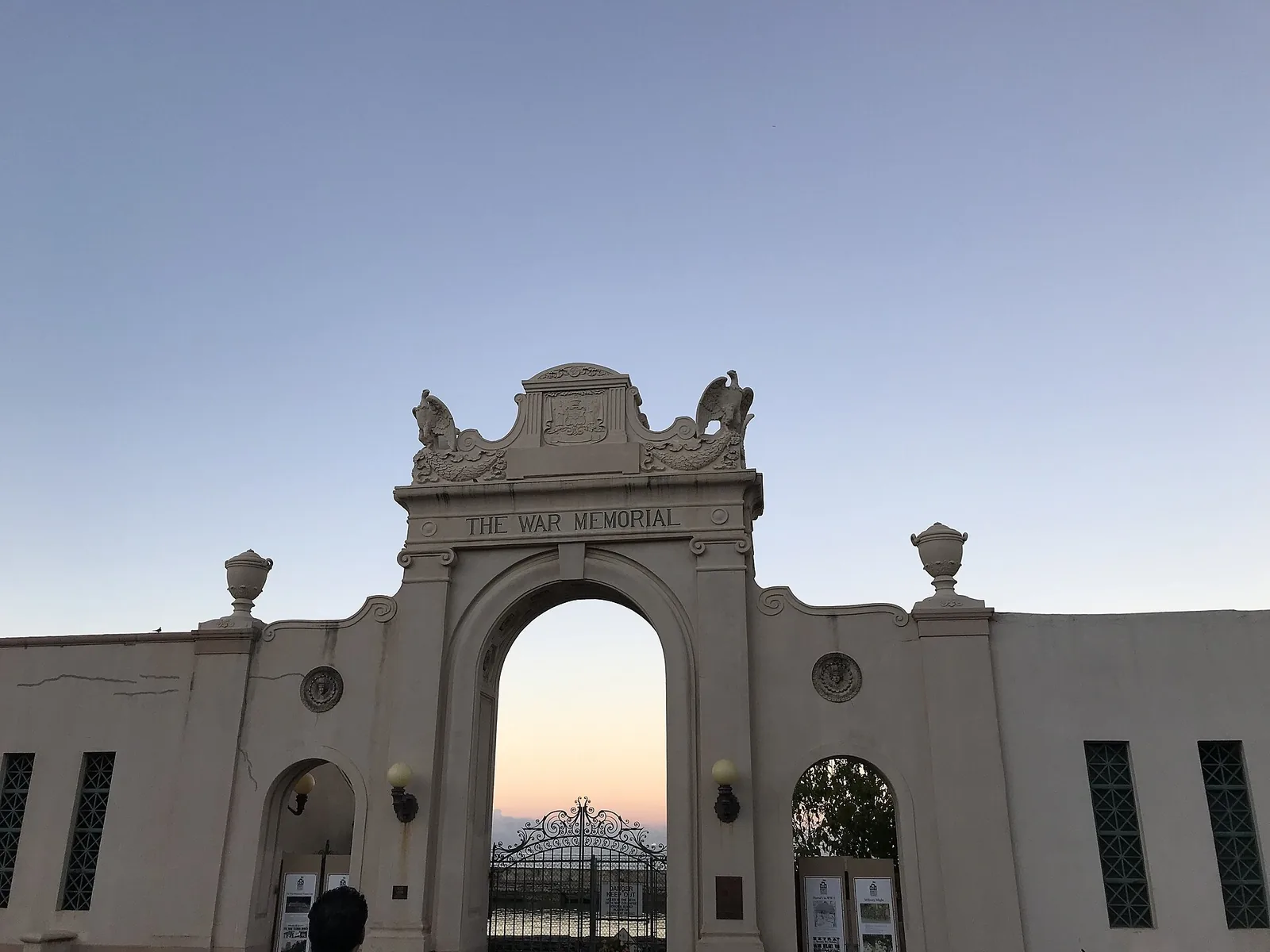 The arched entrance of the Waikiki War Memorial Natatorium against a pale dawn sky